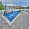 Inground pool with spa, rock waterfall, and slide; gray pavers.
