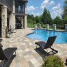 Luxury poolside patio with lounge chairs and multi-toned pavers.
