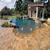 Luxury poolside patio with tan pavers and a tranquil water feature.
