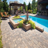 Stone pavers surrounding an in-ground pool and spa; landscaped backyard setting.
