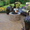 Stone fire pit burning on patio with wicker furniture
