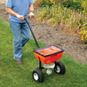 Person using a 50lb spreader on a lawn.
