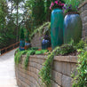 Regal Stone Pro Rockface retaining wall; elegant curved design, enhancing landscaping with lush greenery & large planters.
