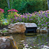 Pond skimmer concealed by rocks and purple flowers.
