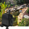 Black magnetic drive pond pump beside a tranquil garden water feature.

