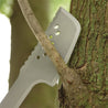 Silver machete cutting a tree branch outdoors.

