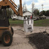 Large, woven polypropylene bulk bag lifted by a forklift, containing aggregate material on a construction site.
