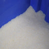 Off-white polymer granules in a blue container.
