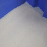 Off-white polymer beads in a blue container.
