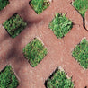 Grasstone II 80mm permeable paving: Red-brown brick pavers with square cut-outs for grass growth, creating a unique landscape design.
