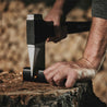 Axe being sharpened on a compact sharpener, outdoors.
