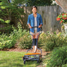 Woman using a manual reel mower on a lush green lawn.
