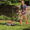 Man using a reel mower on a sunny lawn.
