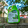 Green insect killing soap concentrate bottle outdoors on a wooden fence.
